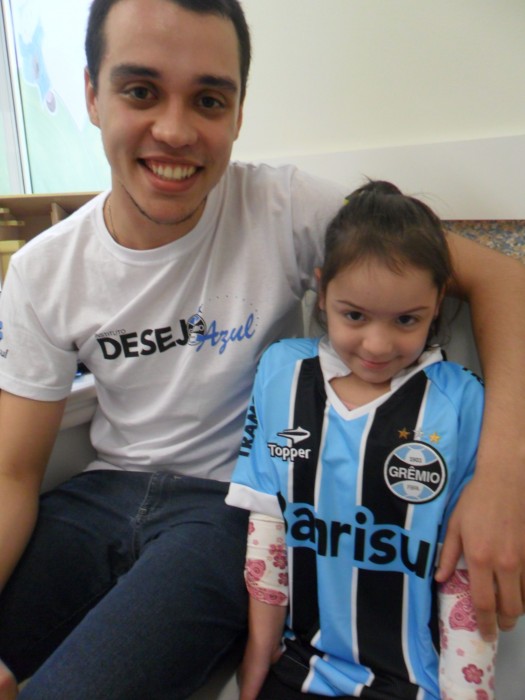 Estava estampado no olhar e no sorriso da menina a alegria ao receber sua camiseta do Grêmio. A menina de 6 anos que faz tratamento de saúde no Hospital Conceição recebeu do voluntário João Paulo Capelari de Lucena um kit completo com camiseta personalizada, calção e meia do Tricolor. 
