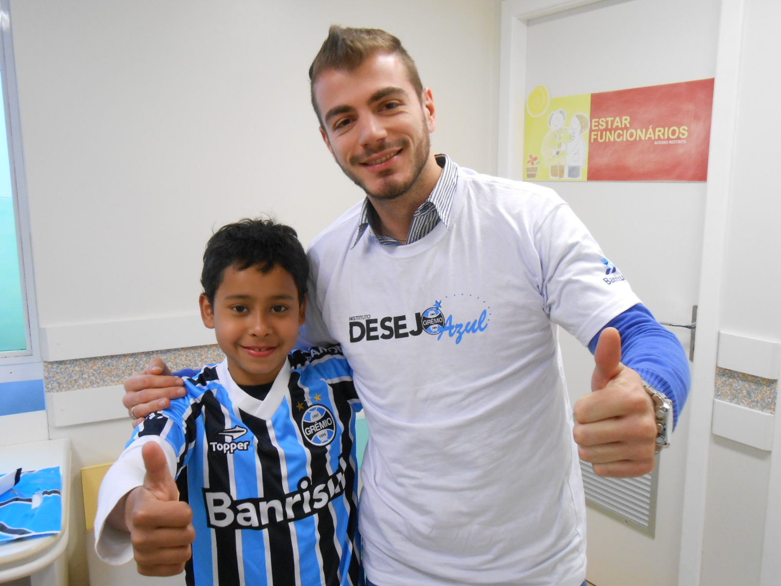 Gustavo faz tratamento no Hospital Conceição. Está praticamente curado da sua enfermidade. Está fazendo somente consultas preventivas. Logo estará com toda saúde do mundo para jogar sua bola E como grande gremista que é seu desejo era ganhar um uniforme completo do Grêmio. Com a ajuda do voluntário Gustavo Baurmann levamos até o menino o kit completo com camiseta personalizada, calção e meia do Imortal Tricolor