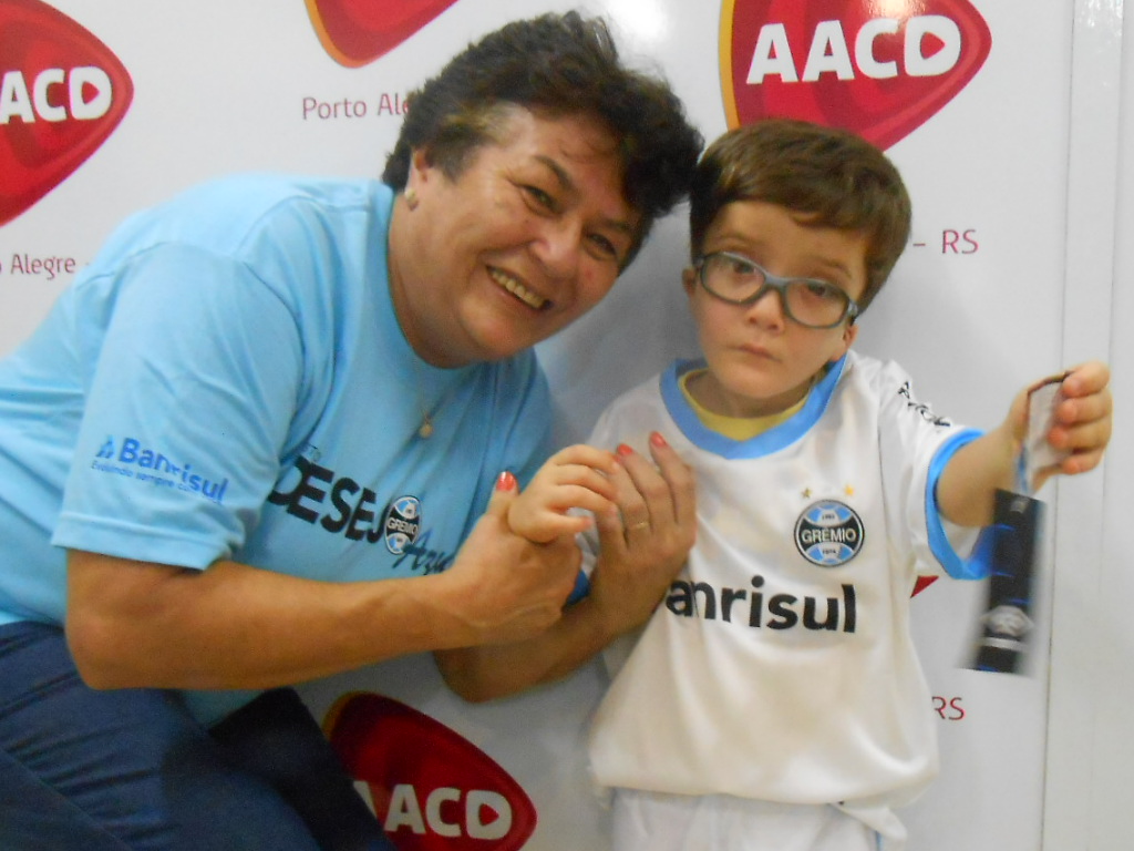 João Miguel faz tratamento na AACD. Seu desejo era ganhar um uniforme completo do Grêmio. E o menino pode comemorar a vitória de ontem vestindo sua camiseta nova. A ação contou com a voluntária Maria da Graça Larsen.