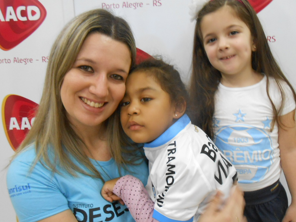 A menina Mariani, seu pai e sua avó presentes na ação, a voluntária Bruna Koszeniewski e sua filha, além de Felipe seu marido todos presentes na AACD estavam muito felizes. A pequena Mariani vestiu orgulhosa a camiseta do Grêmio e abriu um largo sorriso de felicidade.