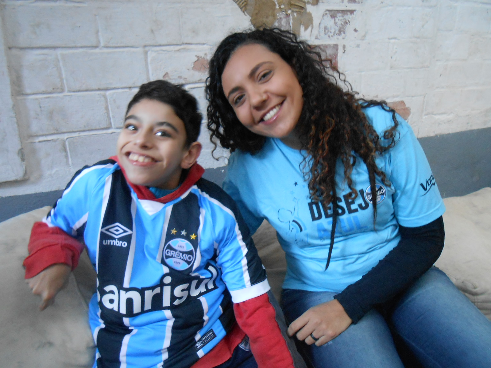 Wesley tem 12 anos e faz tratamento na APAE de Canoas. Vibrou muito quando a voluntária Victória Oliveira chegou com seu presente azul. Na hora o menino não vacilou e de pronto vestiu a camiseta tricolor personalizada com seu nome com orgulho.