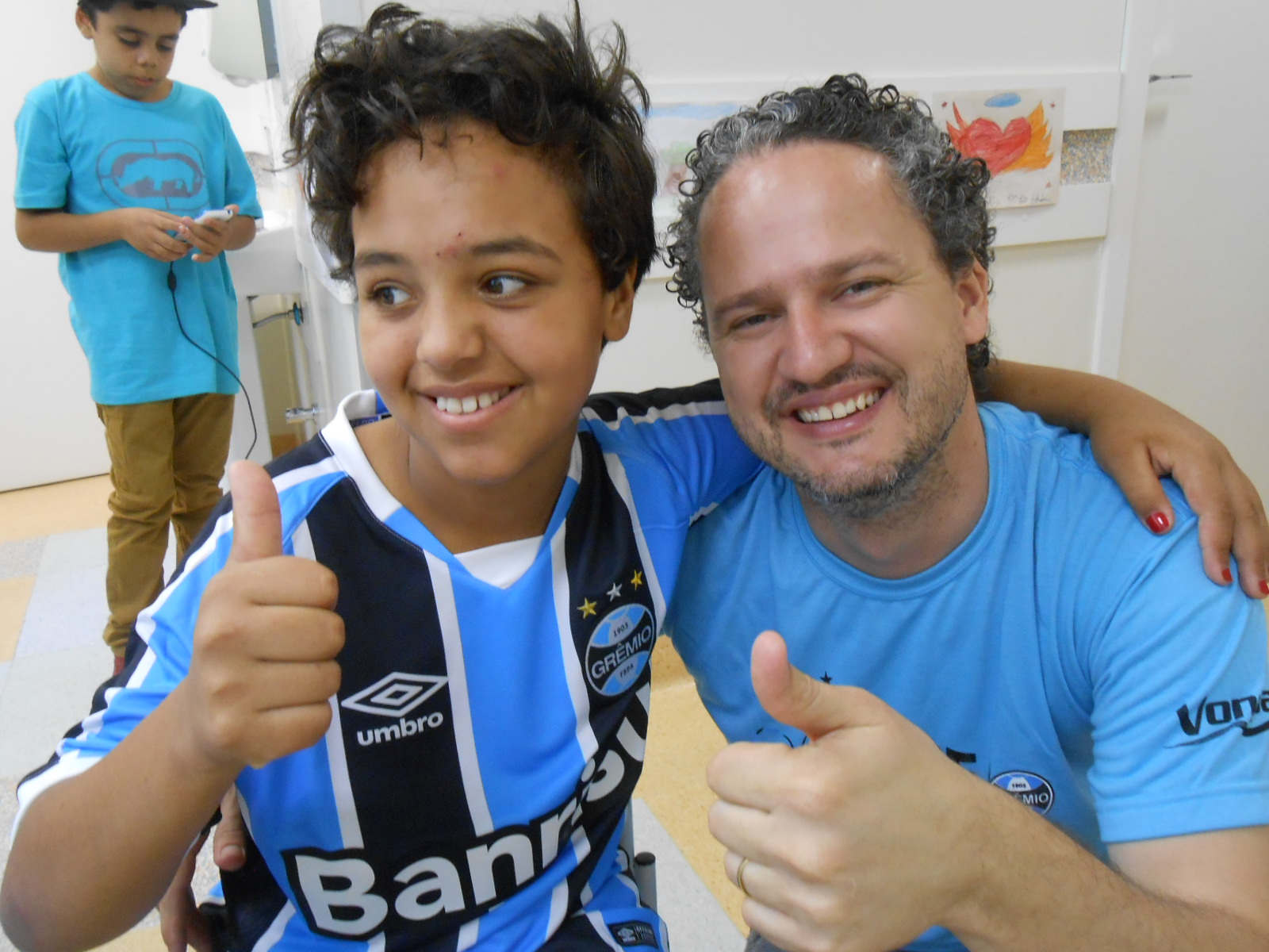 Emanueli é de Fagundes Varela / RS e faz tratamento no Hospital Conceição. É uma menina de 9 anos dona de um largo sorriso cativante. Alegre e otimista vai como boa gremista que é ganhar essa batalha. Emanueli ganhou sua camiseta oficial do Grêmio personalizada do voluntário Lurlan Teixeira.