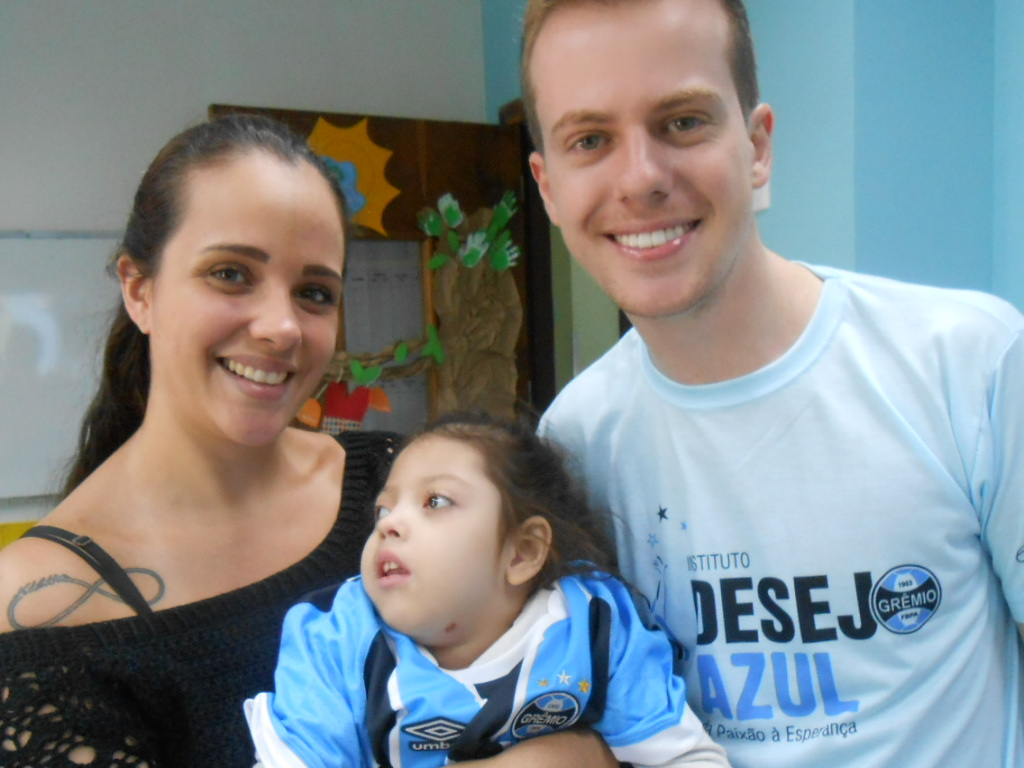 Alice tem 4 anos e faz tratamento na Kinder. Junto com sua mãe aguardava chegar a hora de receber sua camiseta. E este momento chegou com a colaboração do voluntário André. Hoje Alice vai acompanhar o clássico vestindo o manto sagrado tricolor.