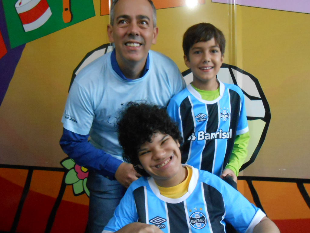 Jô tem 17 anos e faz tratamento no Educandário São João Batista. É uma gremistona de carteirinha e abriu um largo sorriso quando o voluntário Leandro Vidal e seu filho Pedro abriram para a menina a camiseta oficial do Grêmio bem como outros presentes azuis.