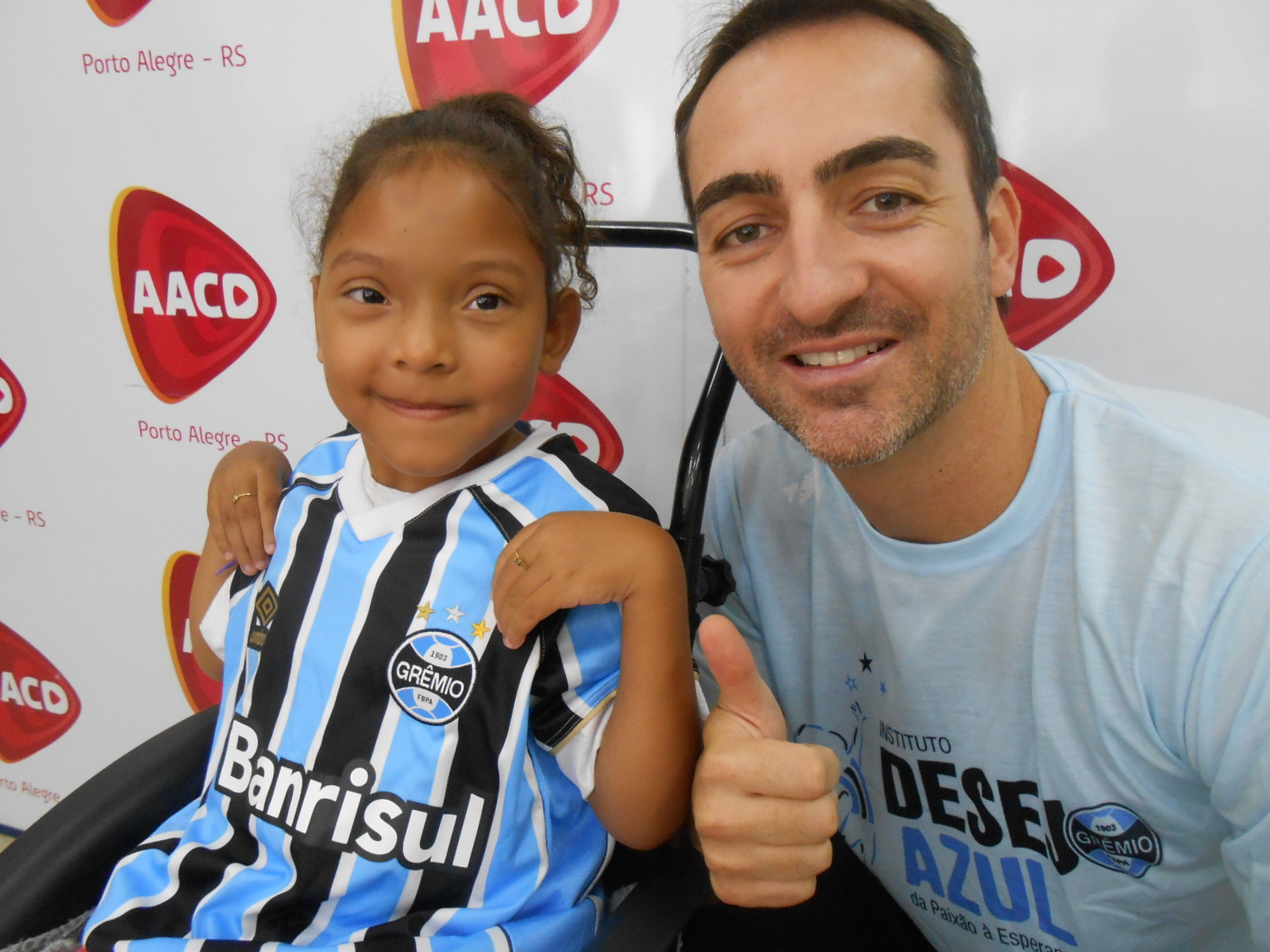 Júlia faz tratamento na AACD de Porto Alegre. A menina tem sete anos e além de guerreira tem personalidade pois das três irmãs é a única gremista. Por isso Júlia vestia orgulhosa a camiseta oficial do Grêmio que ganhou do voluntário José Vicente Contursi.