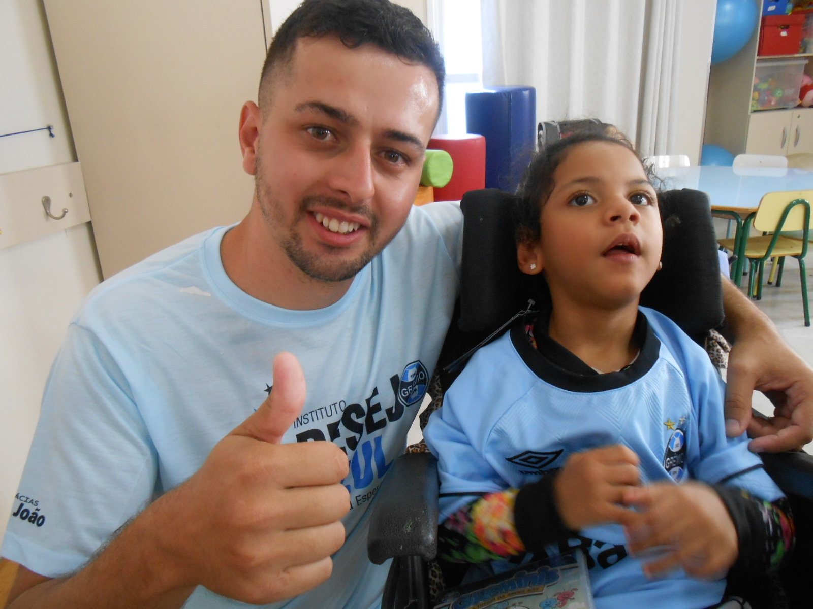 Milena faz tratamento na Kinder. É uma linda gremistinha que não parou um instante quieta enquanto a ação era realizada. Estava muito feliz e entusiasmada enquanto o voluntário Matheus Lopes entregava a ela a camiseta oficial do Grêmio.